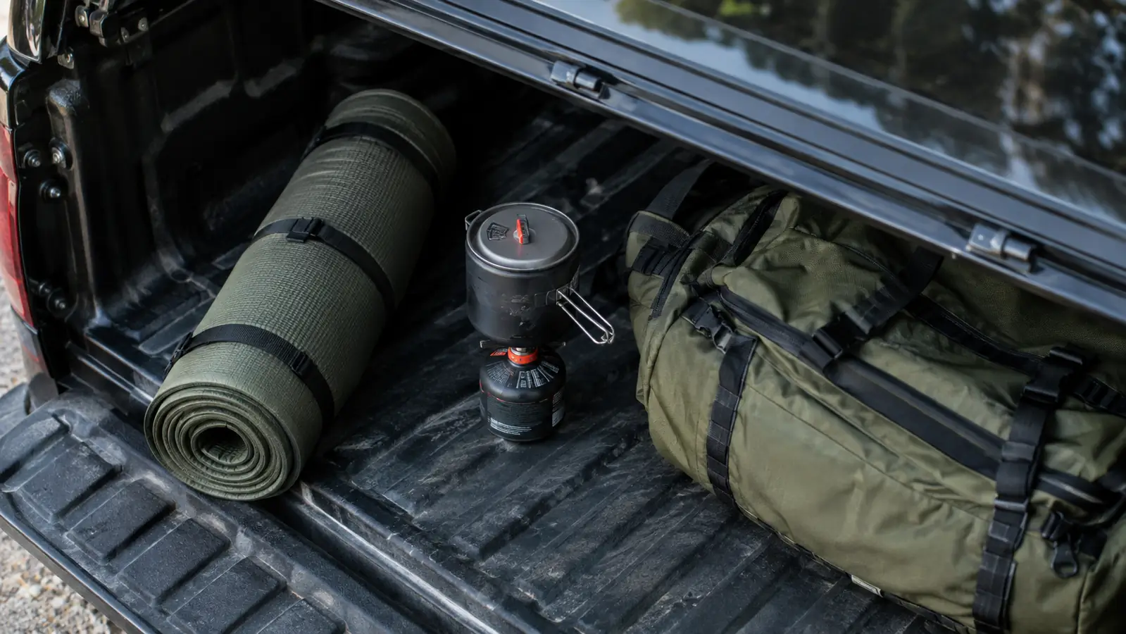 A folded waterproof mat packed with camping gear in the back of a truck